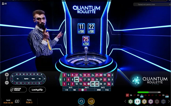 Un barbat prezinta o ruleta Quantum. Numere castigatoare: 11, 22 si 25. 11 si 22 au multiplicator 100x, iar 25 are 250x. Se vad si alte detalii ale layoutului jocului.